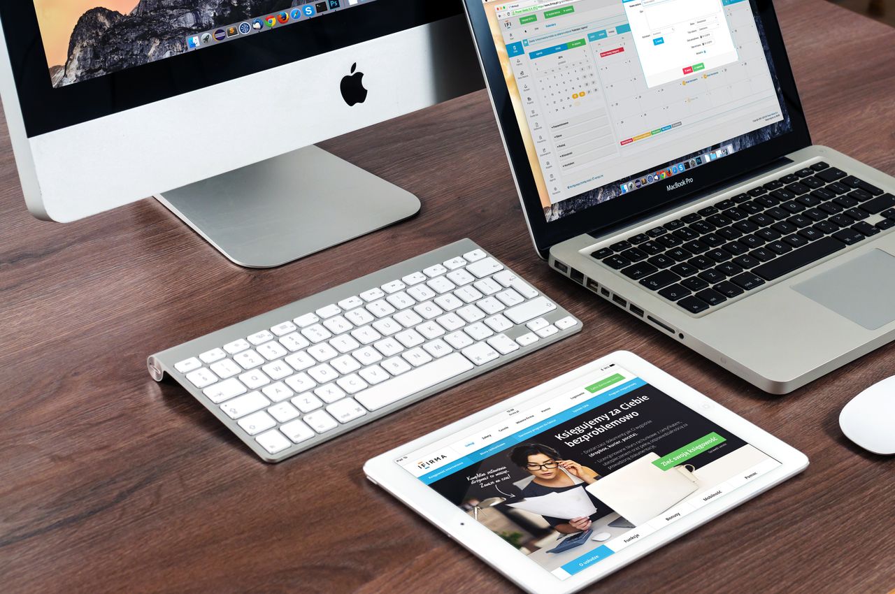 A polished office desk arrangement showcasing Apple devices: iMac, MacBook, and iPad.